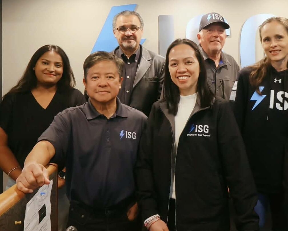 ISG teammates in branded apparel in front of the company wall